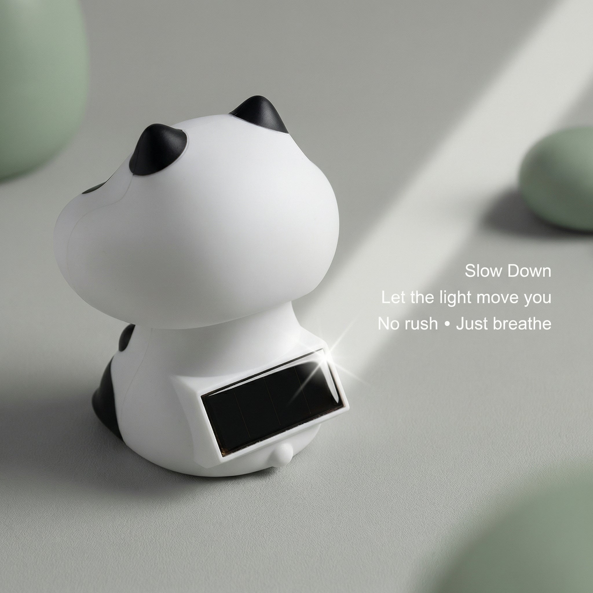 Back view of solar panda figurine showing built-in solar panel on sage green surface